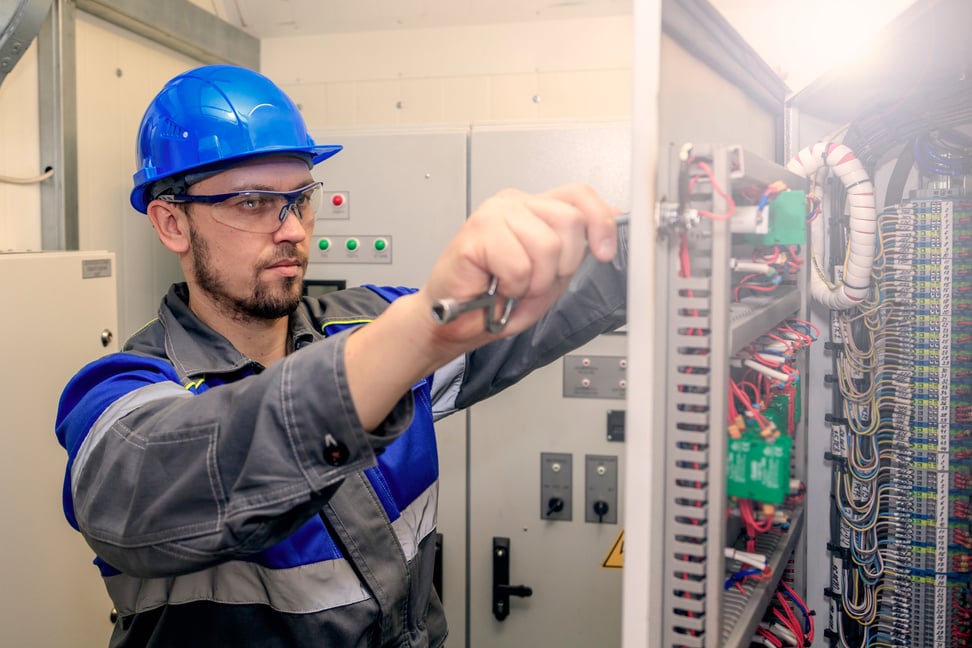 electromechanic in electrical safety gloves holds power cable, cabling connection of high voltage power electric line in industrial distribution fuseboard